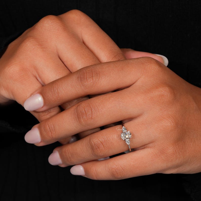 Ring with clear round center stone and pear-shaped clear stones above and below on a polished silver-tone band, worn on hand, front view