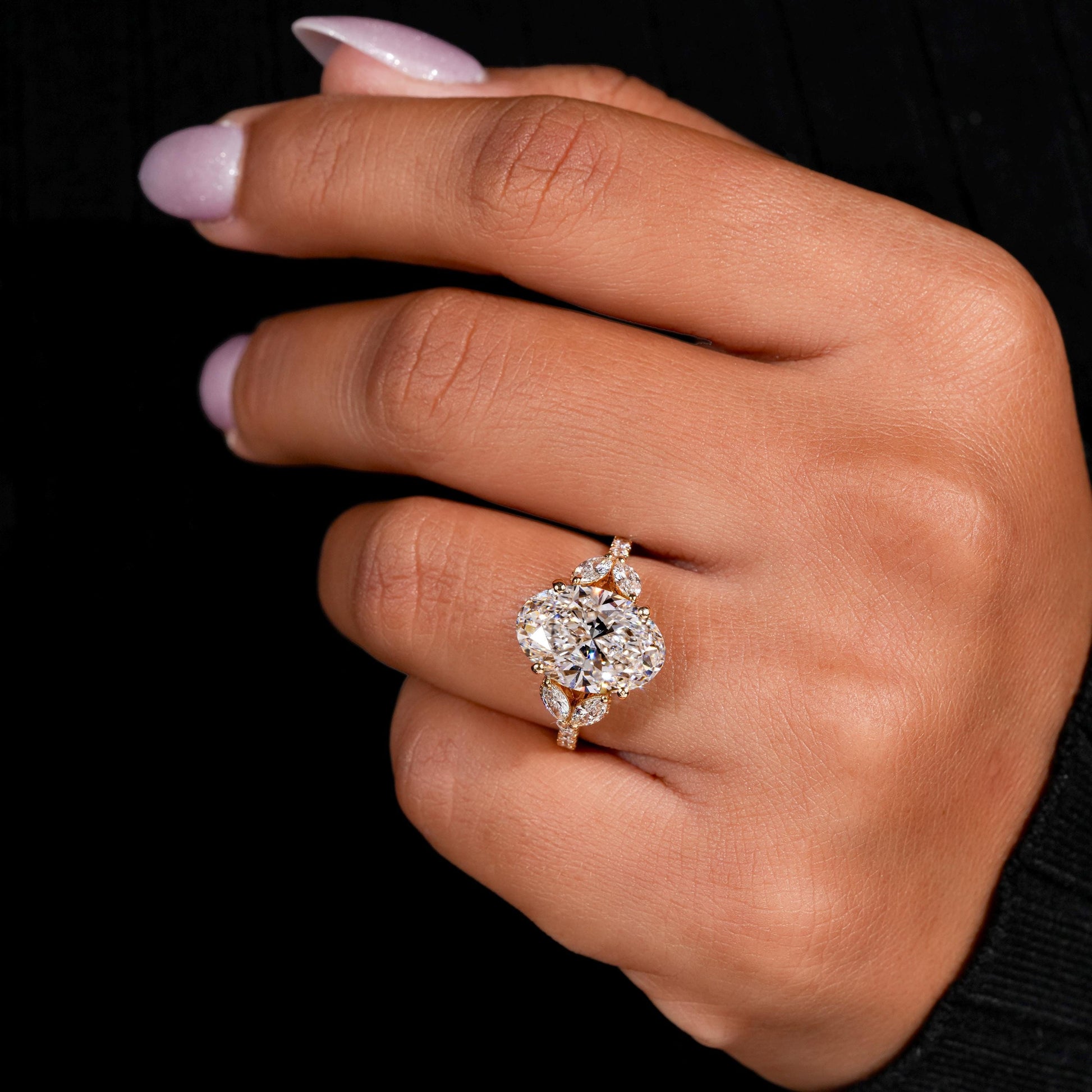 Engagement ring with yellow gold band, four round clear center gemstones in floral cluster design, worn on finger, top view
