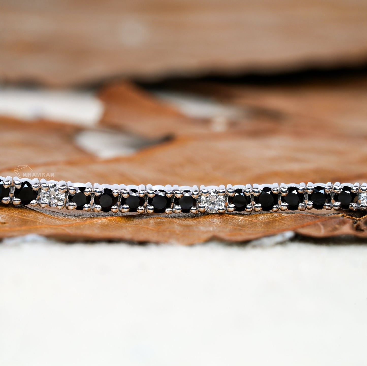 Bracelet with alternating black and clear round stones in a white metal line setting, close-up detail view, tennis bracelet jewelry

