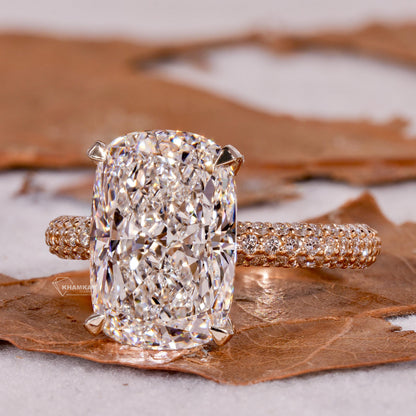 Engagement ring with rectangular clear gemstone, polished yellow metal pavé band, four-prong setting, front angled view
