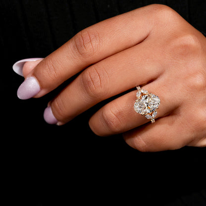 Engagement ring with yellow gold band, oval clear center gemstone, marquise side stones, worn on finger, angled hand view
