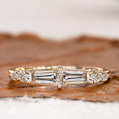 Engagement ring with rose gold band, horizontal baguette-cut clear center gemstone and round side stones, front view
