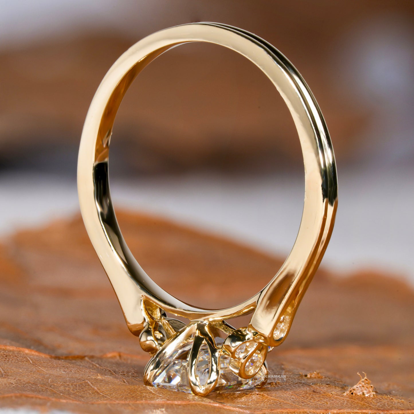 Engagement ring with yellow metal band, open gallery, floral-inspired undergallery, rectangular clear gemstone, rear view
