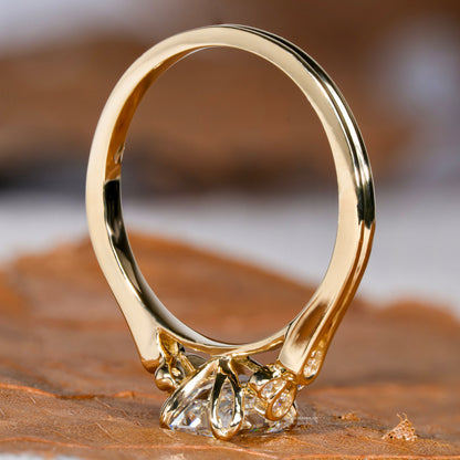 Engagement ring with yellow metal band, open gallery, floral-inspired undergallery, rectangular clear gemstone, rear view
