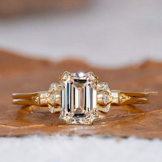 Engagement ring with rectangular clear gemstone, yellow metal band, leaf-inspired side accents with round stones, front view
