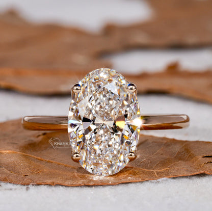 Engagement ring with white metal band, elongated oval solitaire gemstone in four-prong setting, front view

