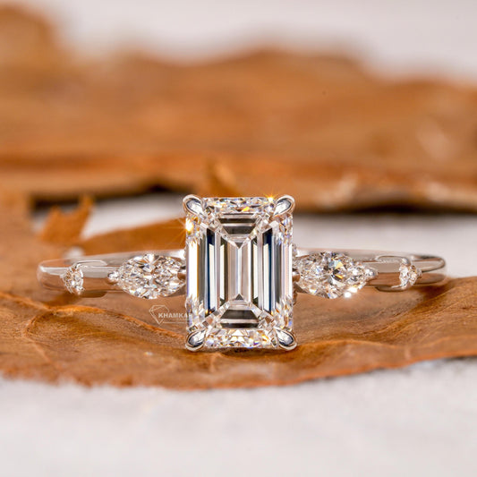 Engagement ring with white metal band, emerald-cut clear center stone, marquise side stones and round accents, front view
