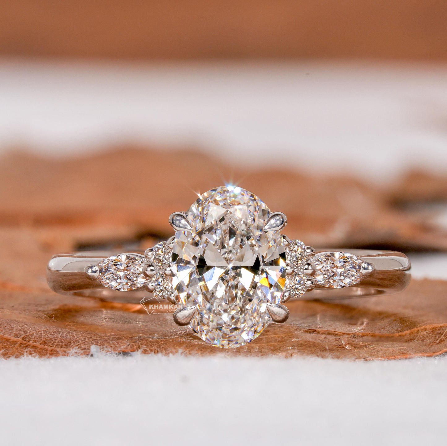 Engagement ring with oval clear center gemstone, marquise side stones, polished white metal band and front view solitaire design
