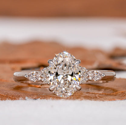 Engagement ring with oval clear center gemstone, marquise side stones, polished white metal band and front view solitaire design
