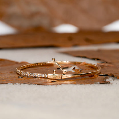 Bracelet with yellow metal band, round stones in a slim tennis bracelet design, open clasp detail, side view on a textured surface
