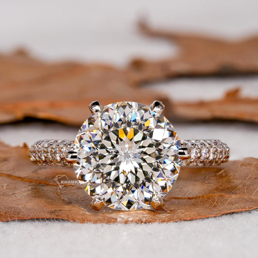 Engagement ring with round clear center stone, white metal pavé band, four-prong solitaire design, front view
