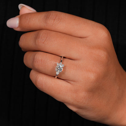 Ring silver-tone band with oval clear center stone and small side stones, worn on a hand, front view