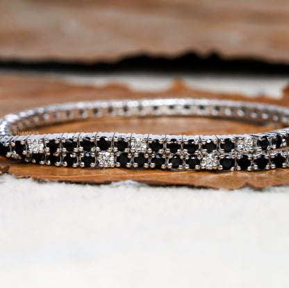 Bracelet with alternating black and clear round stones in a double-row white metal setting, close-up front view, tennis bracelet jewelry
