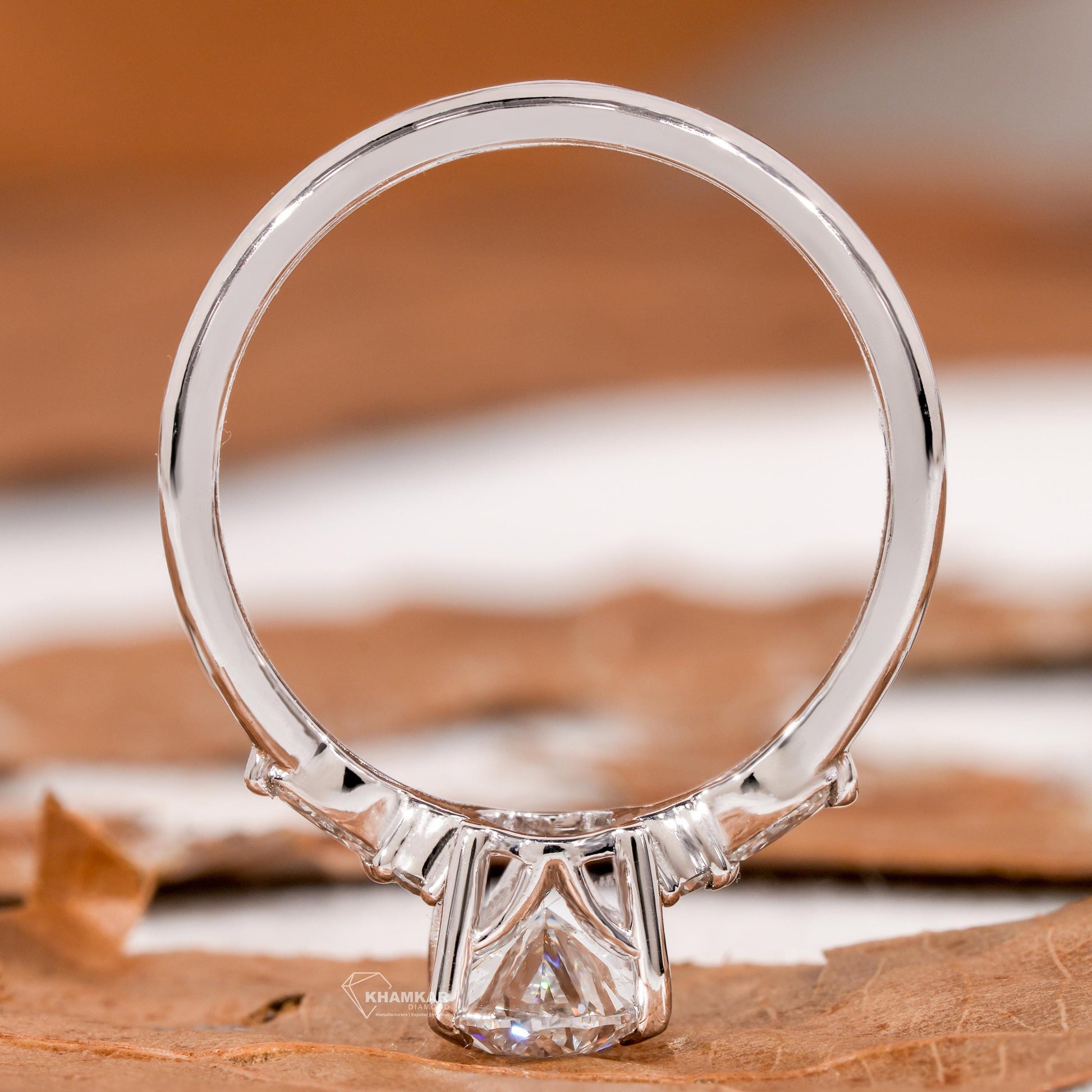 Engagement ring with pear clear center gemstone, polished white metal band and rear view of open basket setting
