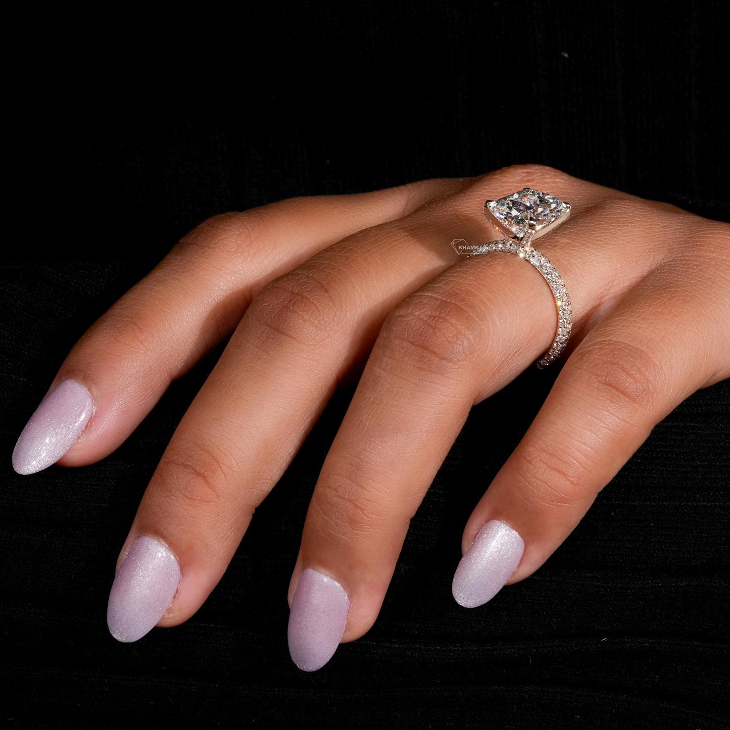 Engagement ring with rectangular clear gemstone, yellow metal pavé band, four-prong setting, worn on finger, side view

