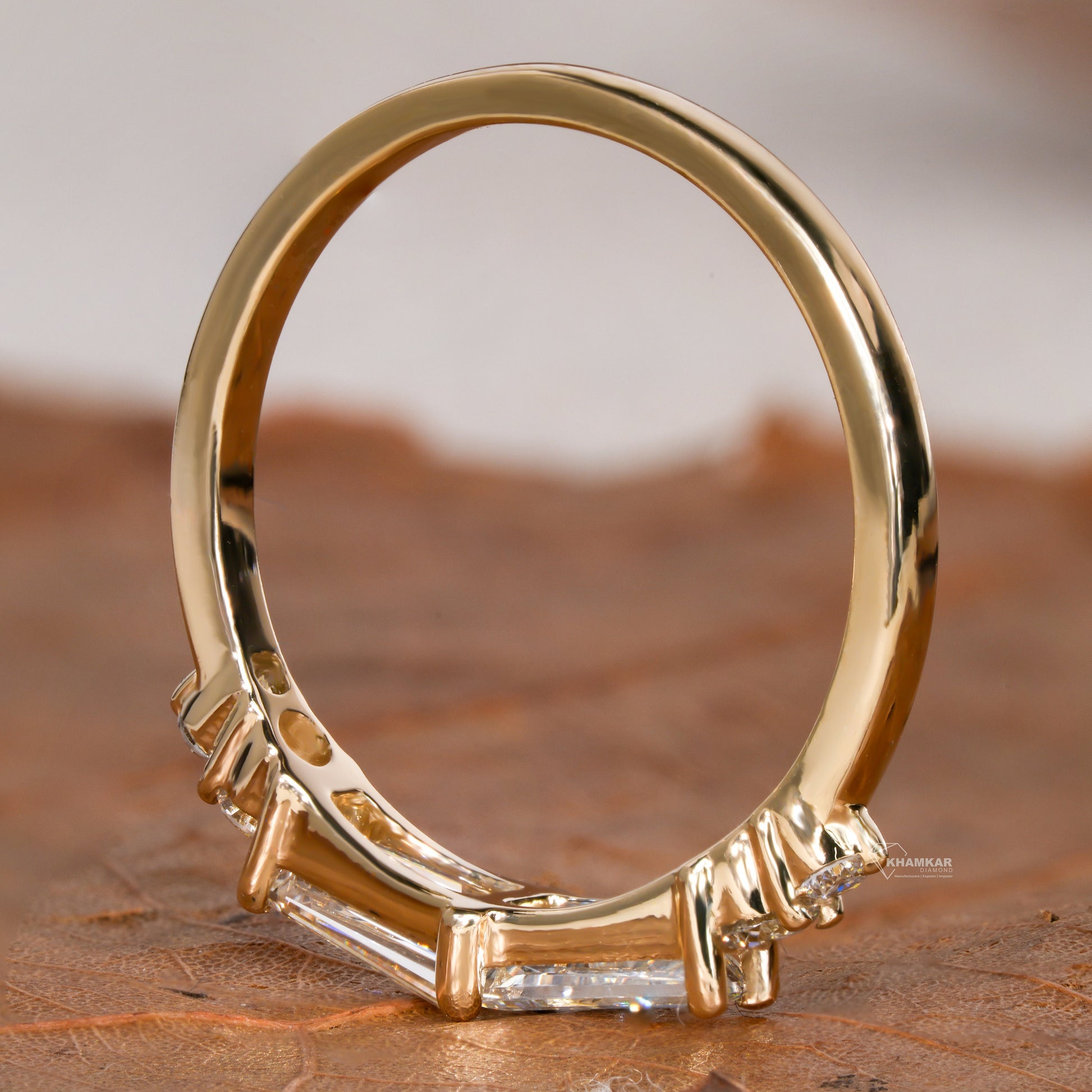 Engagement ring with yellow gold band, tapered baguette-cut center setting and round side stones, side profile view
