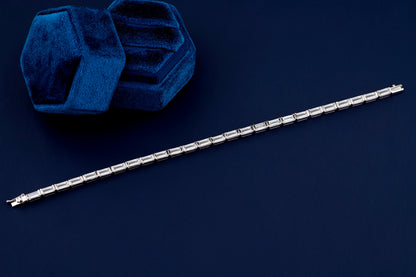 Bracelet with white metal links, rectangular step-cut stones in tennis bracelet design, full-length top view on a dark background
