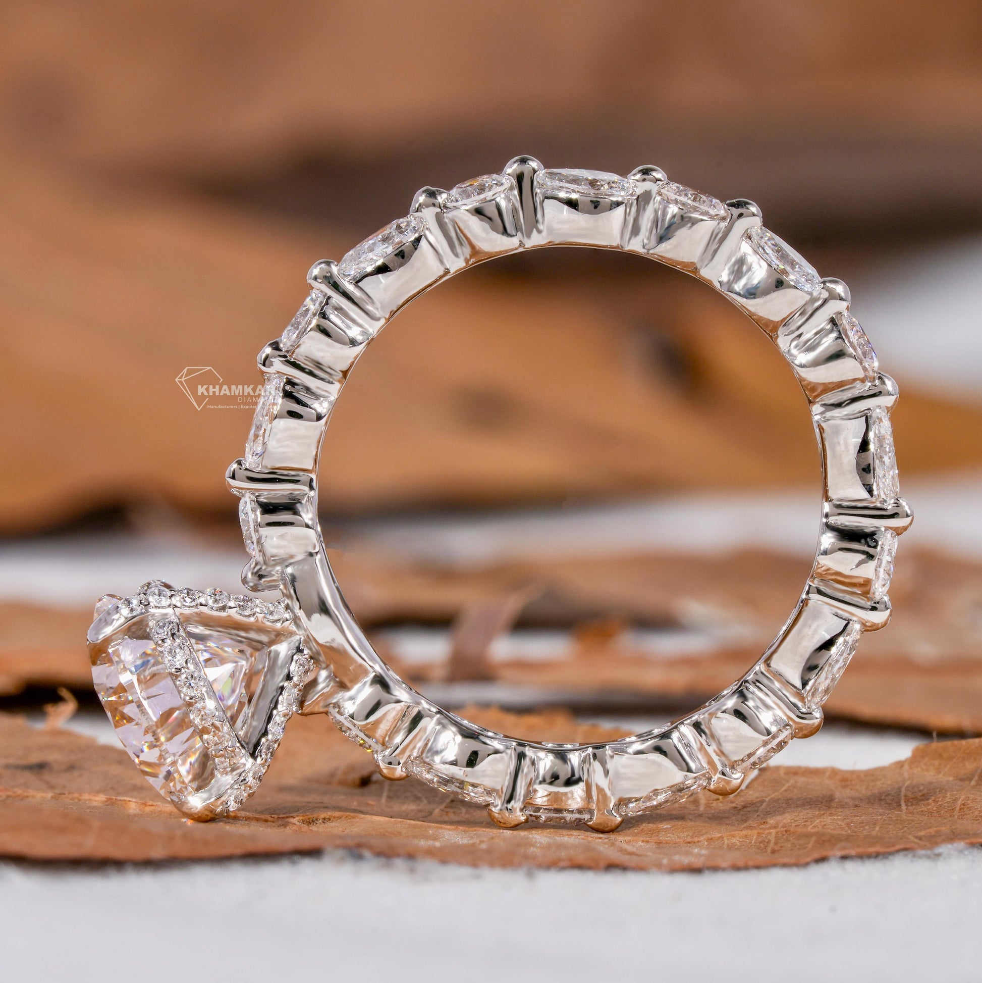 Engagement ring with polished white metal band, pear-shaped clear gemstone, halo setting and pear accent stones, side profile view

