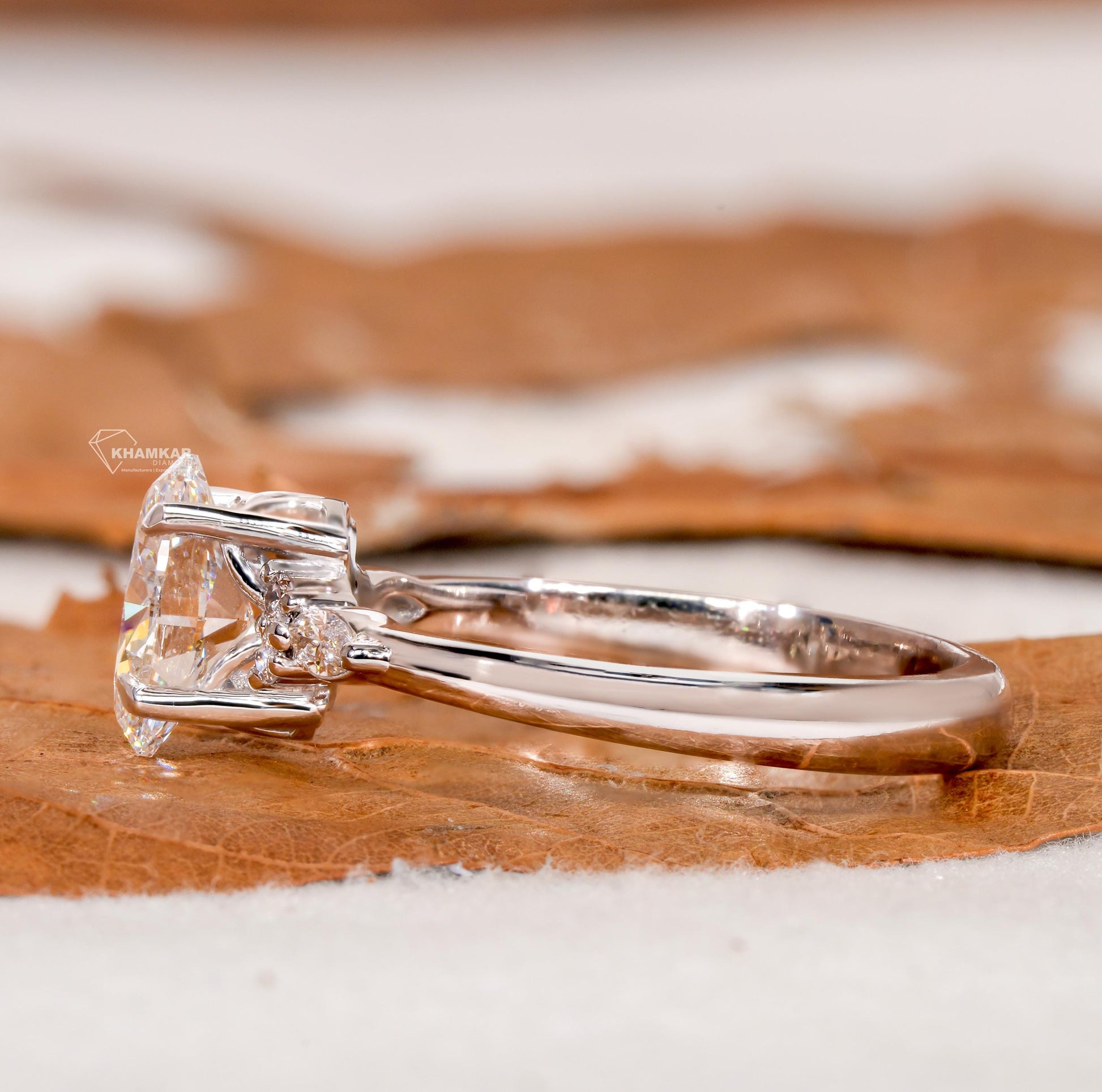 Engagement ring with oval clear center gemstone, polished white metal band, accent side stones and side profile view

