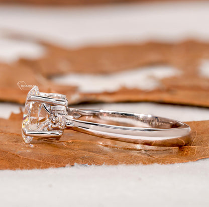 Engagement ring with oval clear center gemstone, polished white metal band, accent side stones and side profile view

