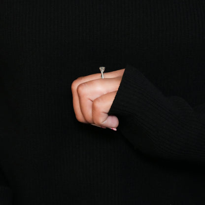 Ring with round clear center stone, twisted white metal band with pavé-set shoulders, side profile worn on a hand
