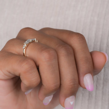Engagement ring with yellow gold band, tapered baguette center setting and round side stones, worn on finger, side angle view
