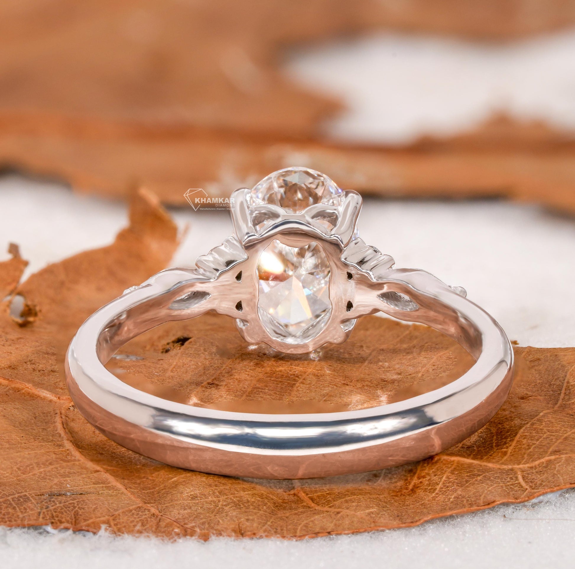 Engagement ring with oval clear center gemstone, polished white metal band, accent side stones and rear view of setting
