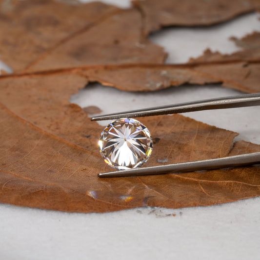 Loose round brilliant-cut diamond held with tweezers, faceted clear stone, pavilion view
