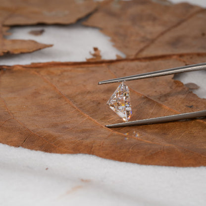 Loose kite-cut diamond held with tweezers, clear faceted gemstone, side profile view with pointed shape visible
