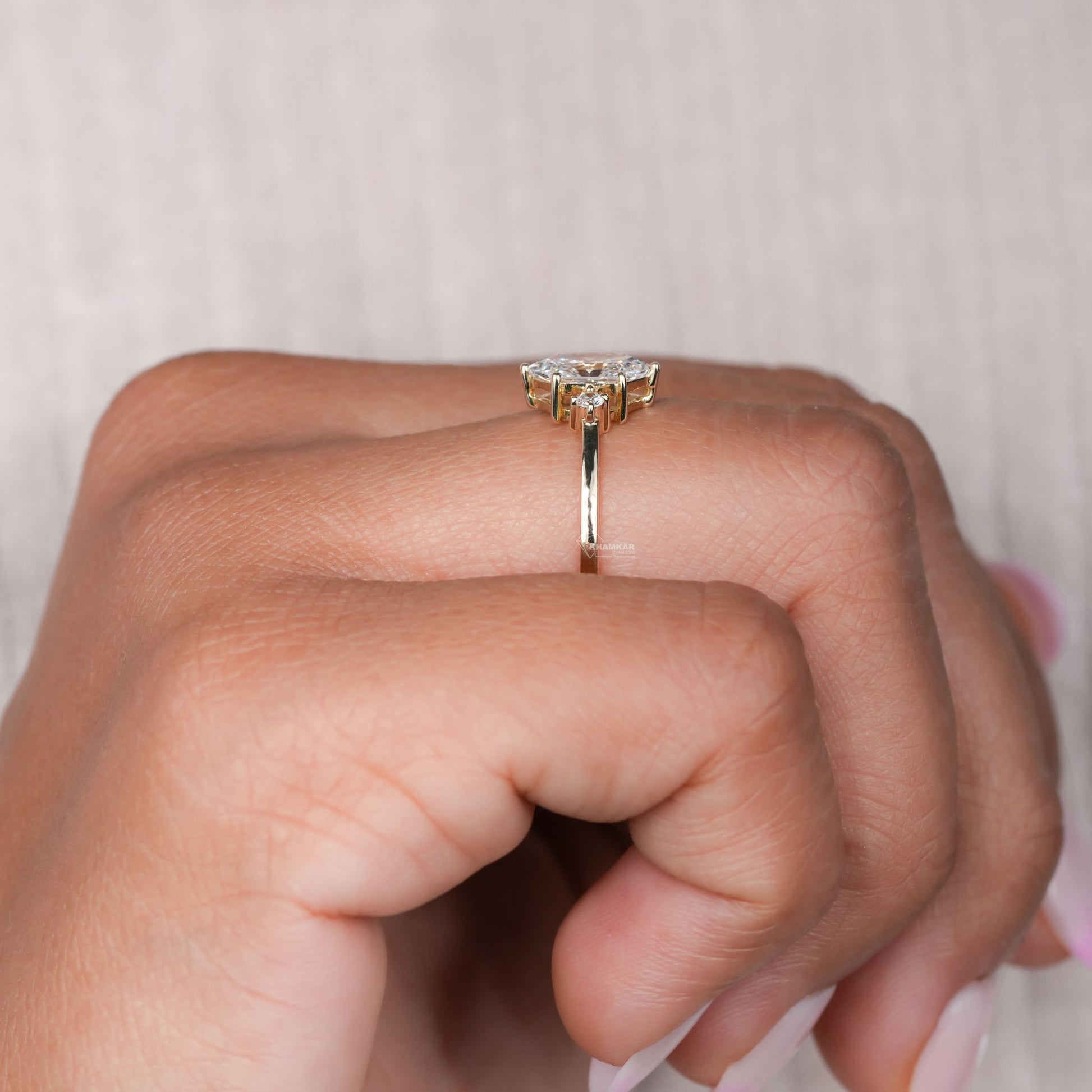 Ring with slim gold-tone band, raised clear stone setting and visible side gallery details, shown worn from a side profile
