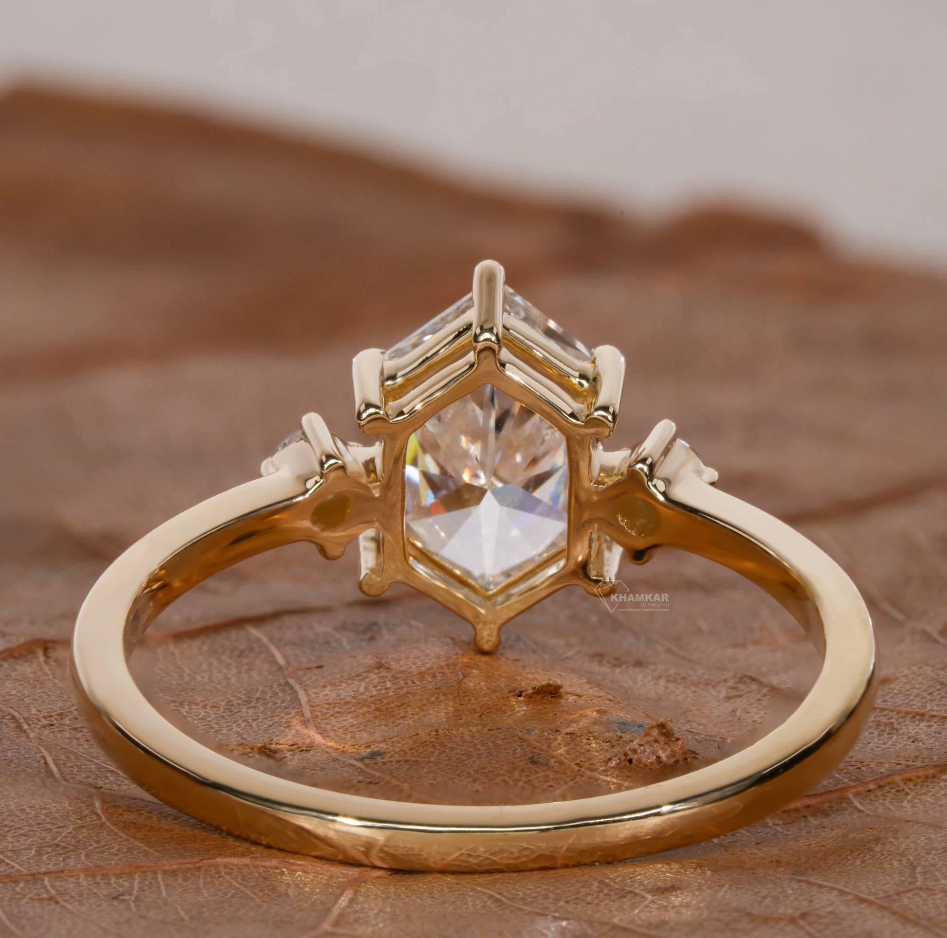 Ring with hexagonal clear center stone, geometric raised setting and polished gold-tone band, shown from the rear view
