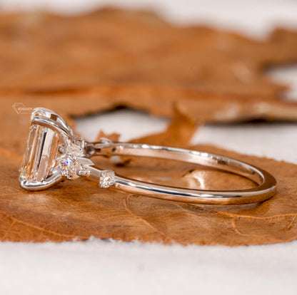 Engagement ring with white metal band, emerald-cut clear center stone, marquise side stones and round accents, side profile view
