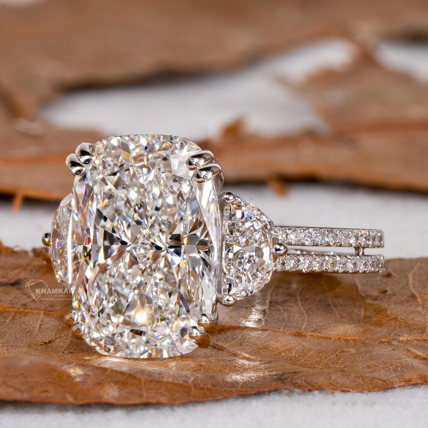 Engagement ring with white metal split shank, elongated cushion-cut clear center stone, oval side stones, angled front view
