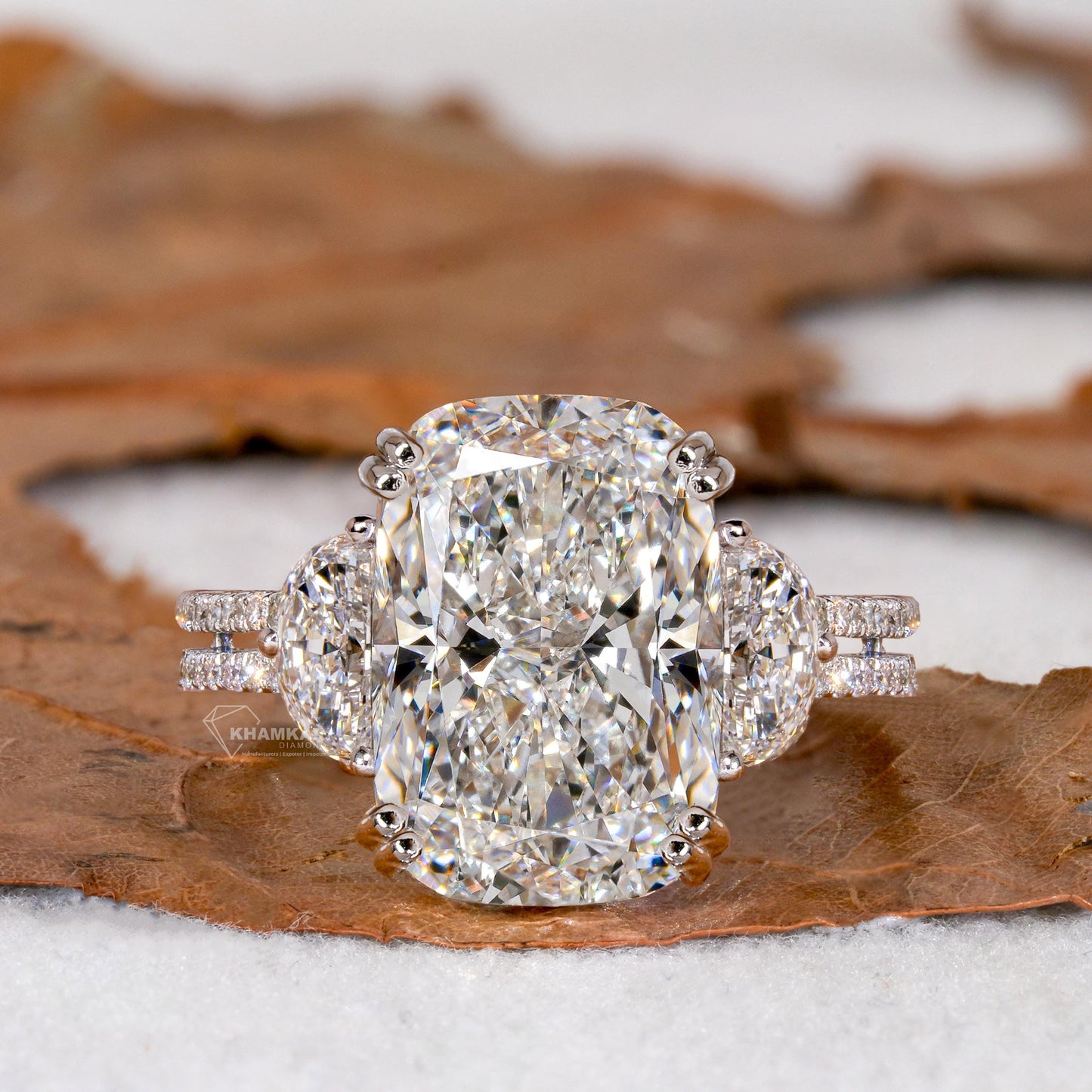 Engagement ring with white metal split shank, elongated cushion-cut clear center stone, oval side stones, front view
