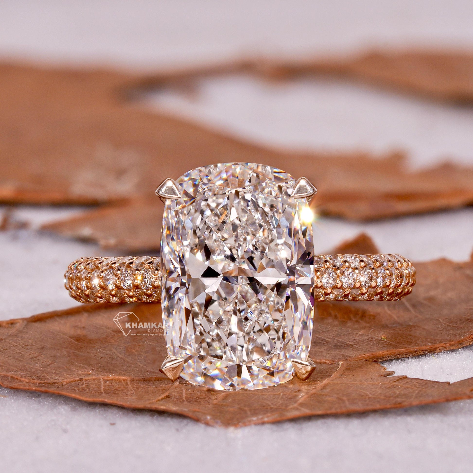 Engagement ring with rectangular clear gemstone, polished yellow metal pavé band, four-prong setting, front view

