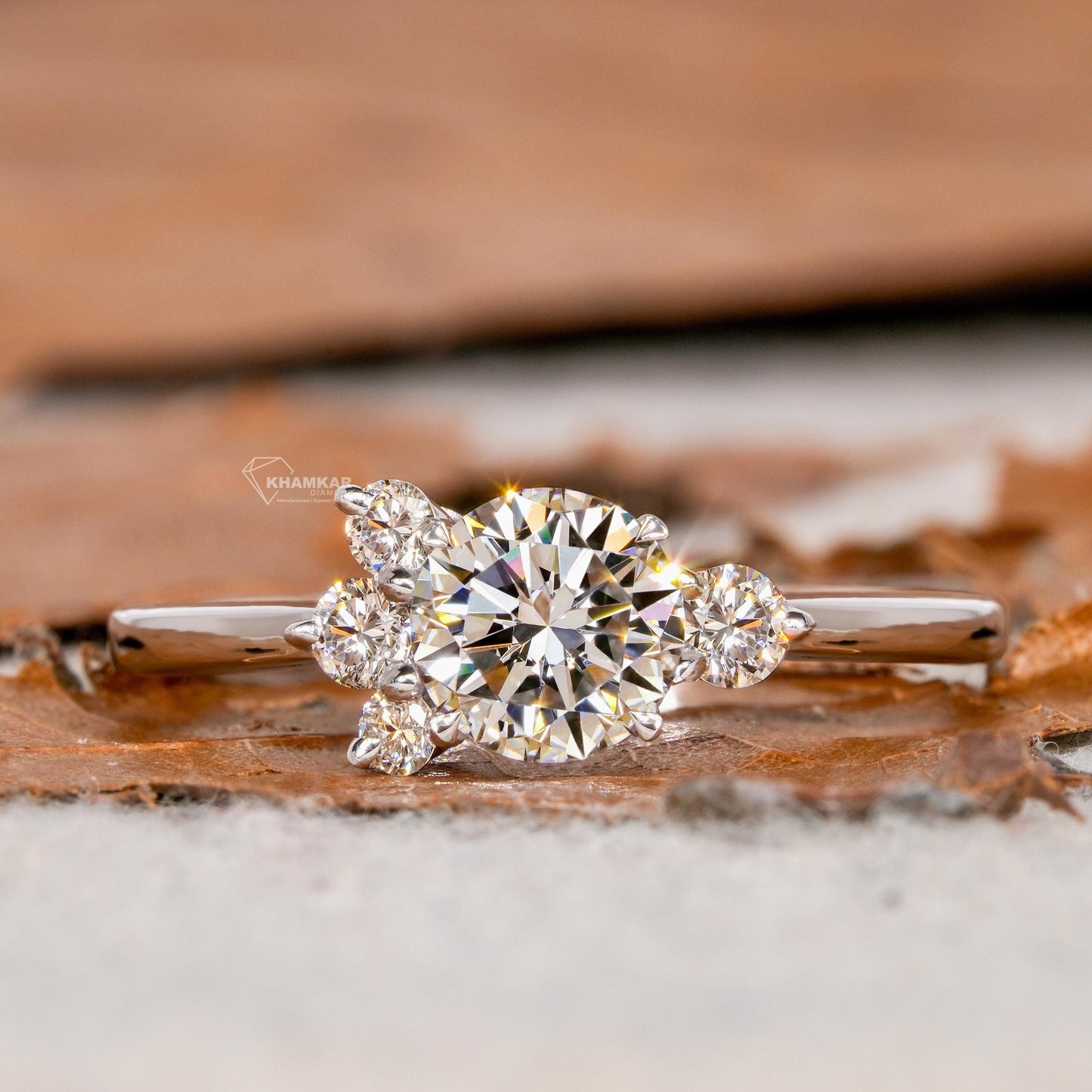 Engagement ring with white metal, round center stone, round side stones, four-stone cluster design, front view
