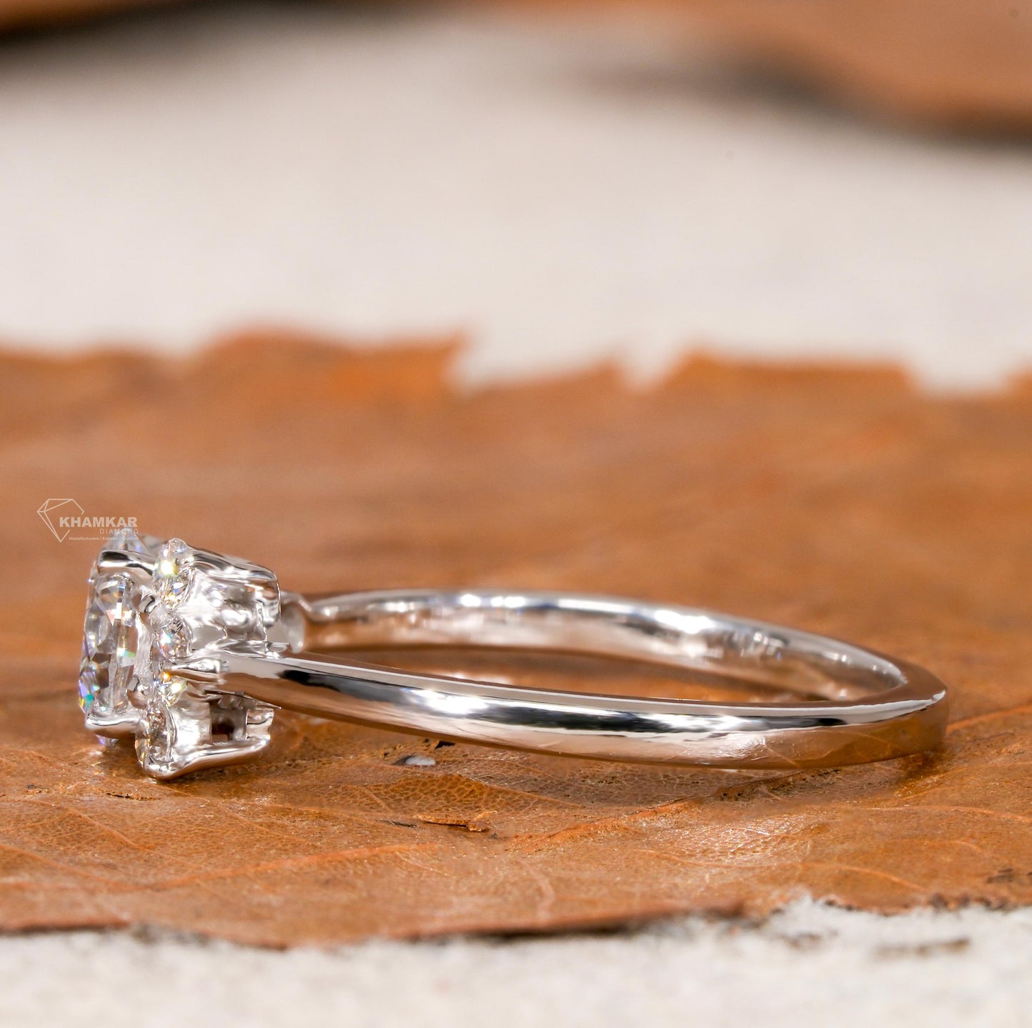 Engagement ring with white metal, round center stone, round accent diamond cluster setting, side profile view
