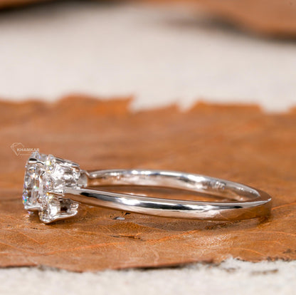 Engagement ring with white metal, round center stone, round accent diamond cluster setting, side profile view
