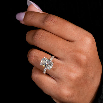 Engagement ring with three clear oval gemstones, yellow metal pavé band, prong setting, worn on finger, angled view
