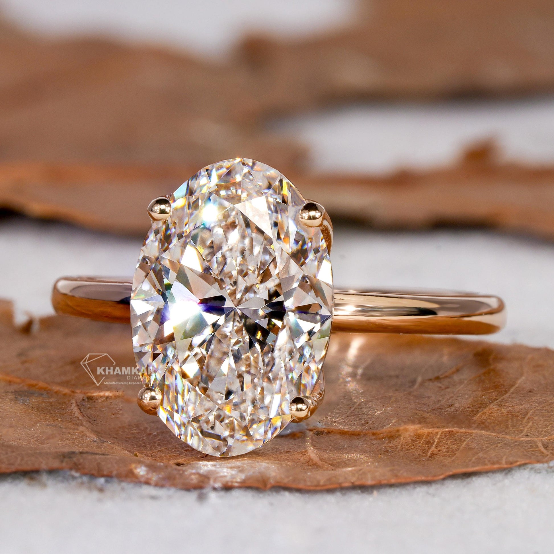 Engagement ring with yellow metal band, oval solitaire gemstone in four-prong setting, front view

