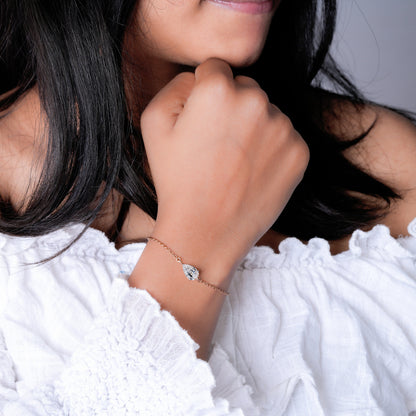 Bracelet with pear-shaped clear stone on yellow metal chain, worn on wrist, close-up lifestyle view, delicate chain bracelet jewelry
