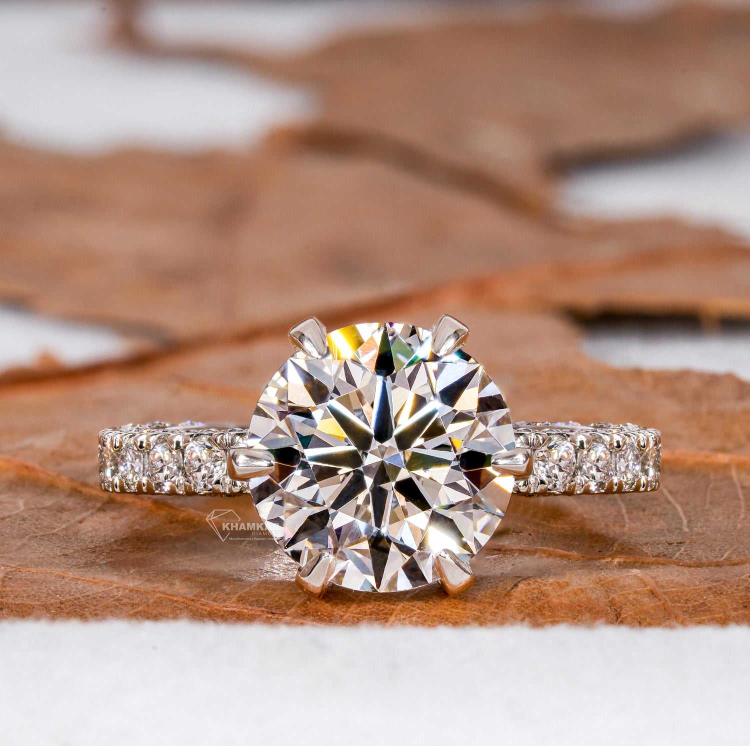 Engagement ring with white metal band, round clear solitaire stone, pavé band and six-prong setting, front view
