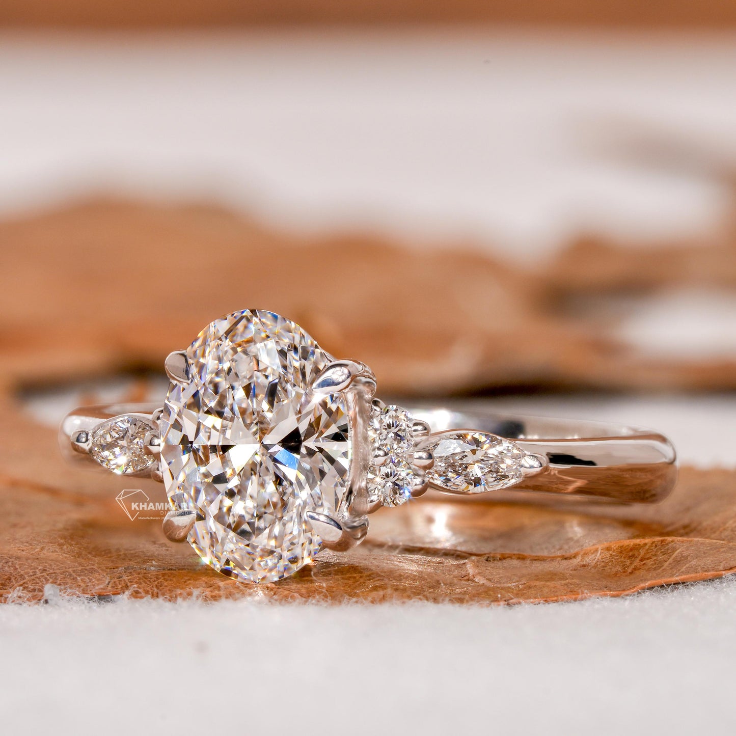 Engagement ring with oval clear center gemstone, marquise side stones, polished white metal band and angled front view
