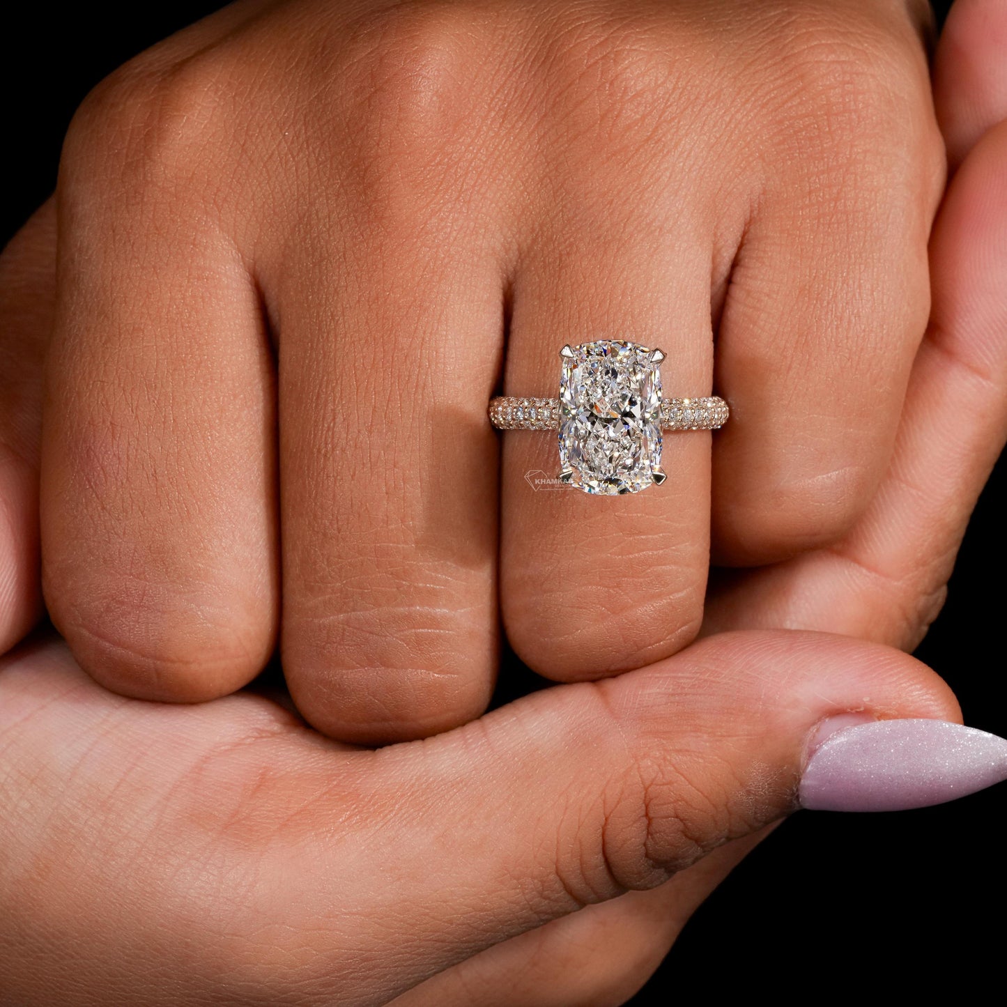 Engagement ring with rectangular clear gemstone, yellow metal pavé band, four-prong setting, worn on finger, front view
