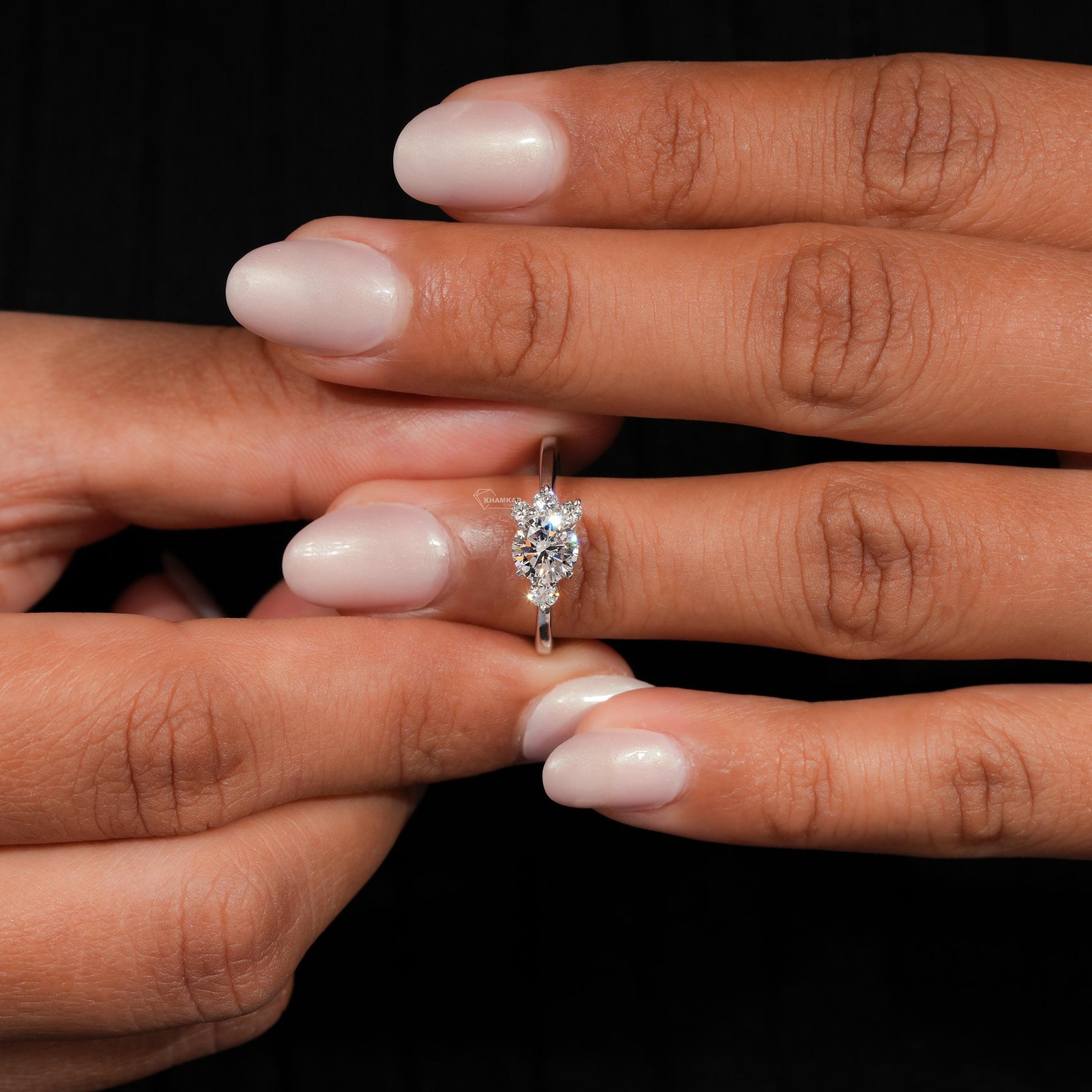 Ring silver-tone band with oval clear center stone and small side stones, worn on finger, side view