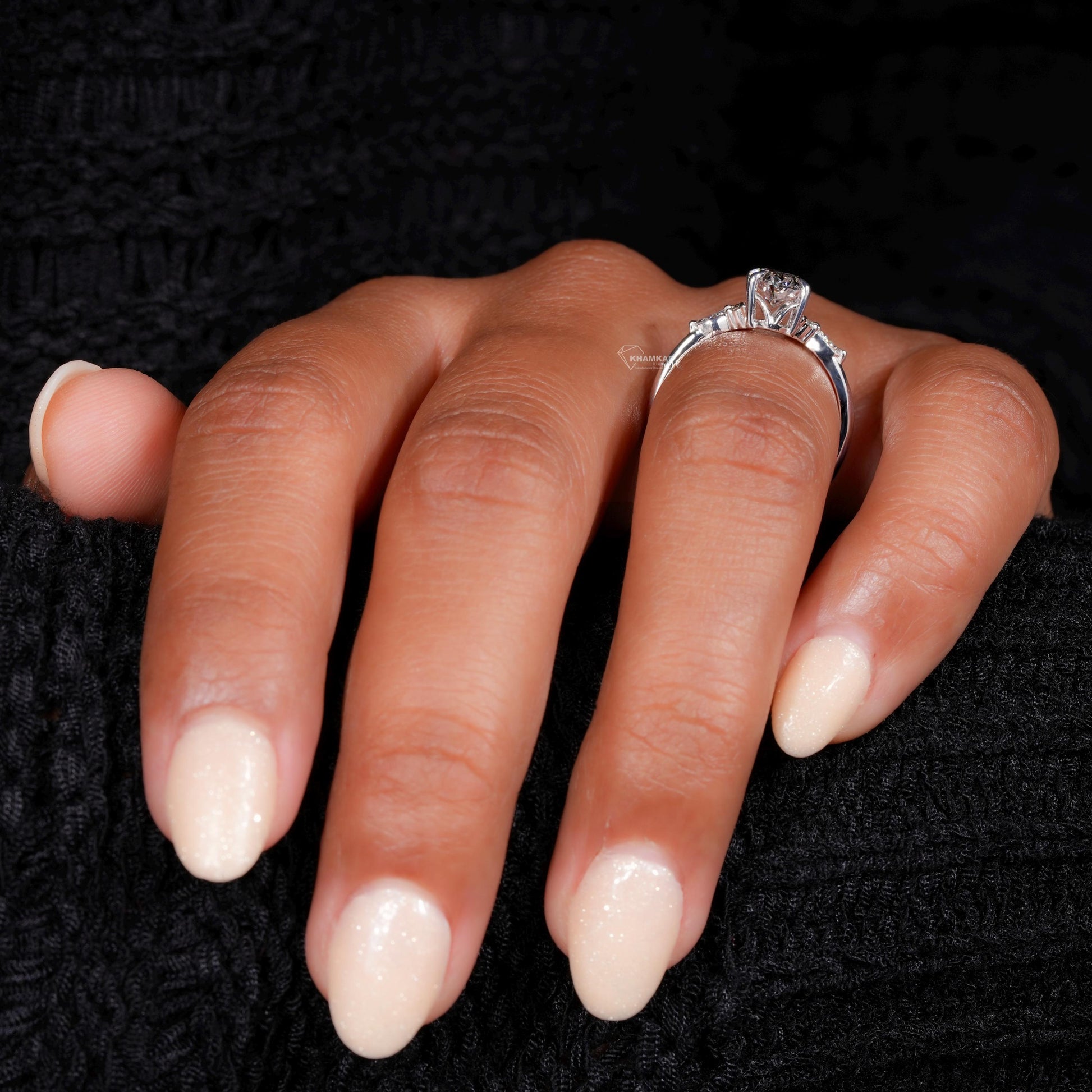 Engagement ring with round clear center gemstone, polished white metal band, accent side stones and side view worn on finger

