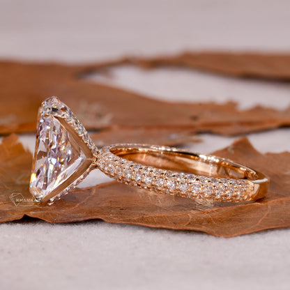 Engagement ring with rectangular clear gemstone, polished yellow metal pavé band, raised four-prong setting, side profile view
