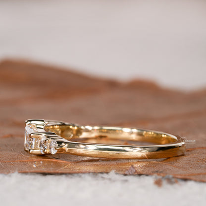 Engagement ring with yellow gold band, horizontal baguette-cut clear center gemstone and round side stones, side profile view
