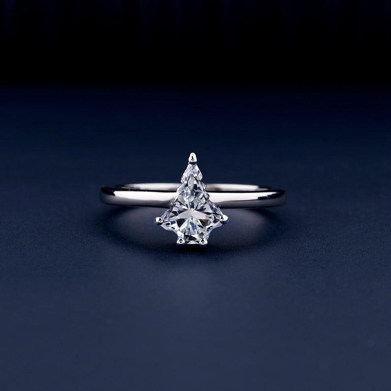 Solitaire ring with clear kite-shaped center stone in prong setting and polished white metal band, front view
