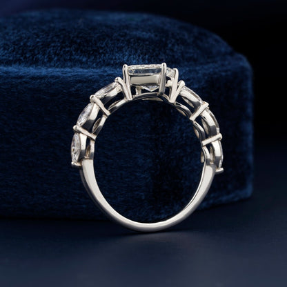Engagement ring with white metal twisted band, princess-cut center stone, marquise side stones, rear view showing open gallery setting on blue velvet display
